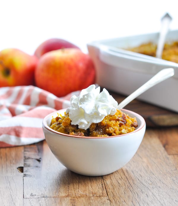 Bowl of southern sweet potato casserole with pecans and topped with dollop of whipped cream
