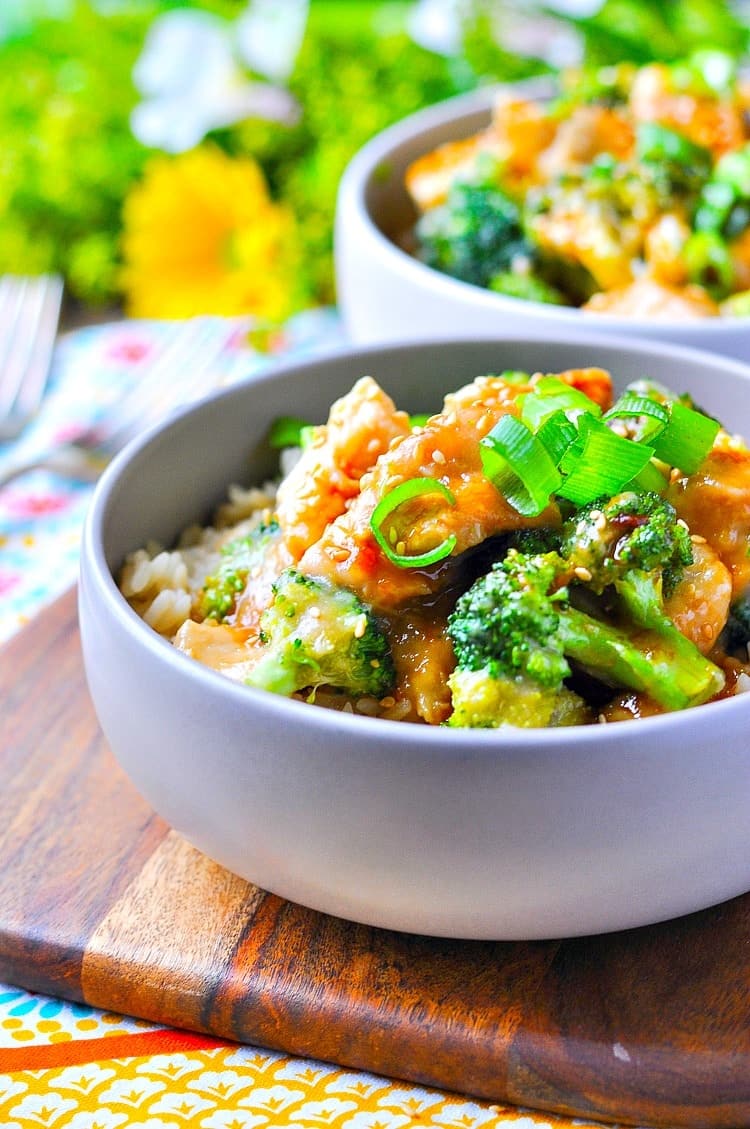 Close up of a bowl of orange chicken in a bowl with broccoli