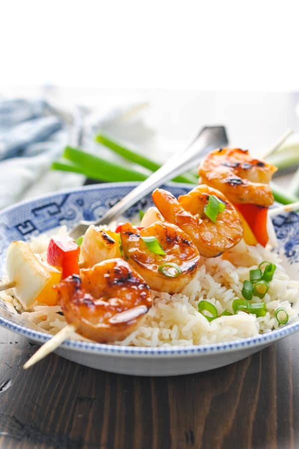 Grilled shrimp skewers on a bowl of rice