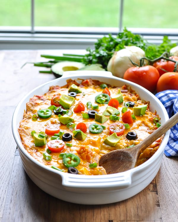 Easy taco casserole with doritos baked in a white dish with a wooden spoon for serving