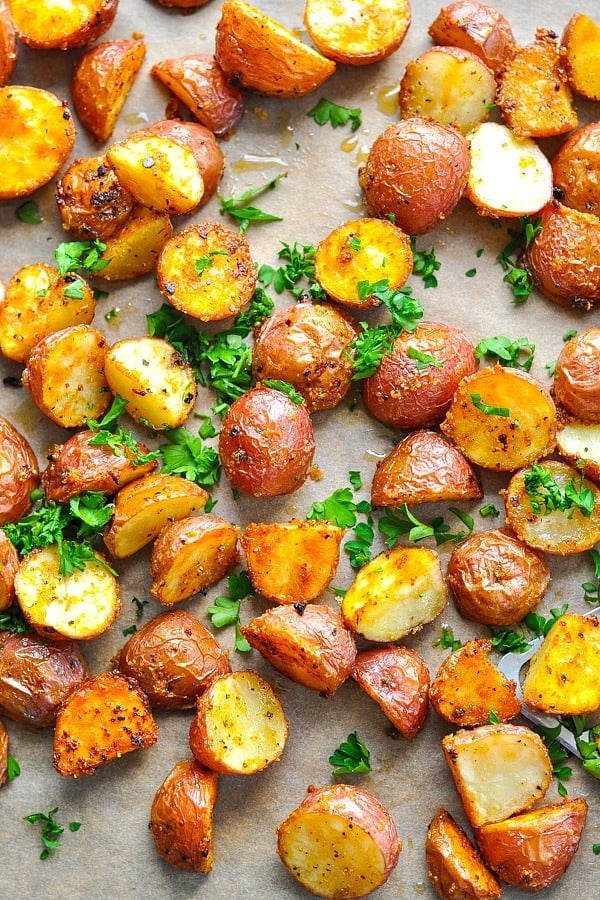 Close up overhead image of Crispy Seasoned Oven Roasted Potatoes on a baking sheet lined with parchment