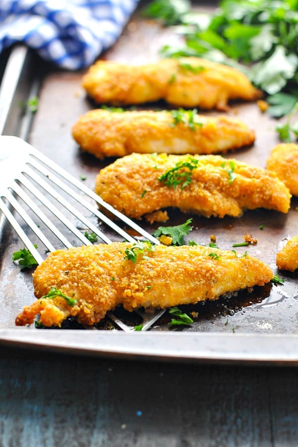 Baked chicken tenders on a sheet pan with spatula