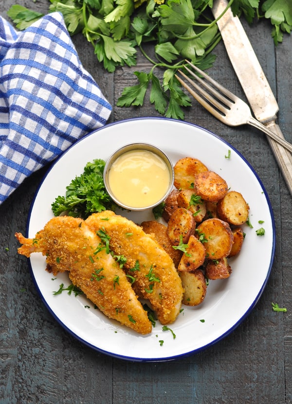 Overhead image of chicken tenders on blue and white plate with side of potatoes