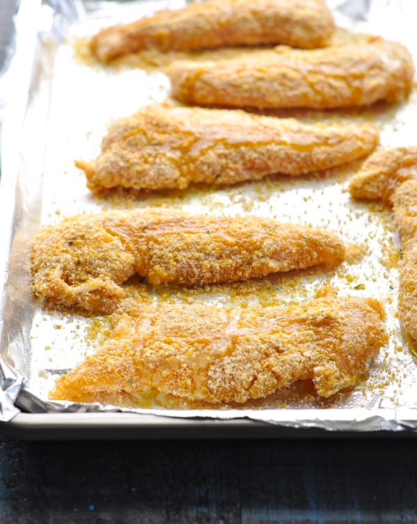 Raw chicken tenders on baking sheet before oven