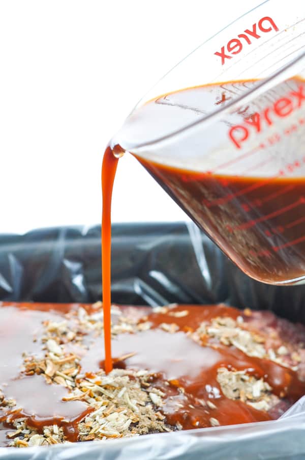 Pouring barbecue sauce over beef brisket in slow cooker