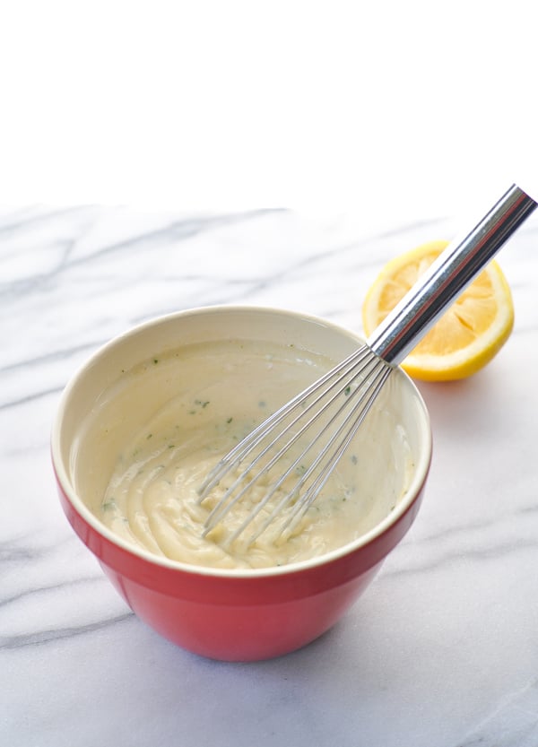 Creamy coleslaw dressing in a red bowl with a whisk