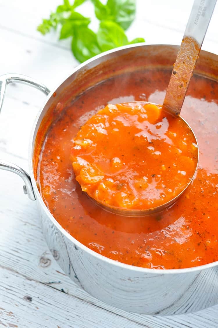 A big pot of marinara soup with a ladle scooping some out