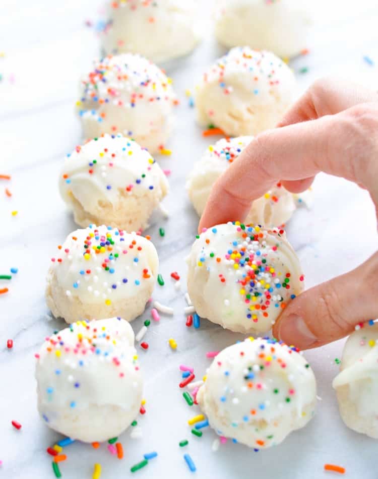 Hand picking up a Champagne Cake Ball with rainbow sprinkles