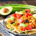 Plate of crock pot chicken nachos piled high with toppings