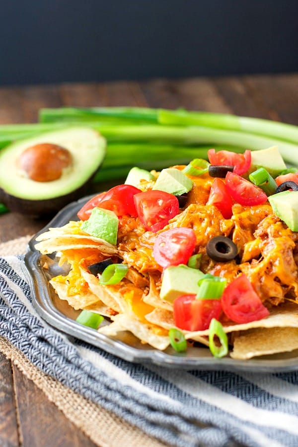 Plate of crock pot chicken nachos piled high with toppings