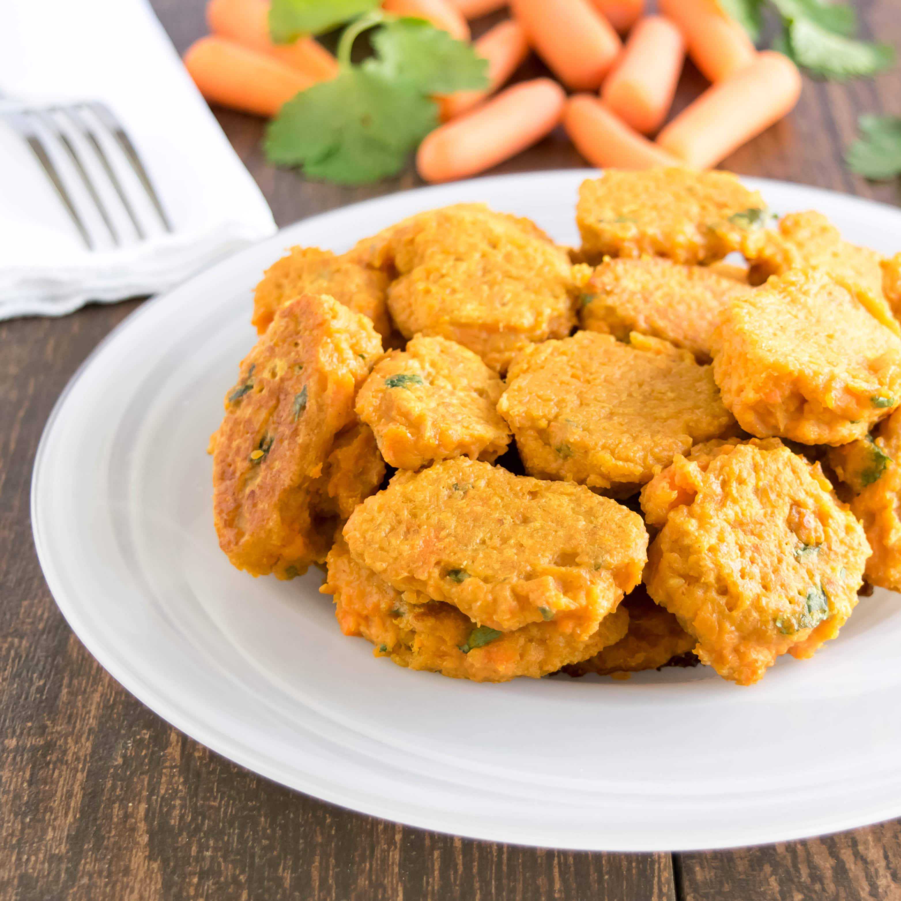 A plate full of healthy carrot fritters, made with carrots and vegetables and served on a white ceramic plate.