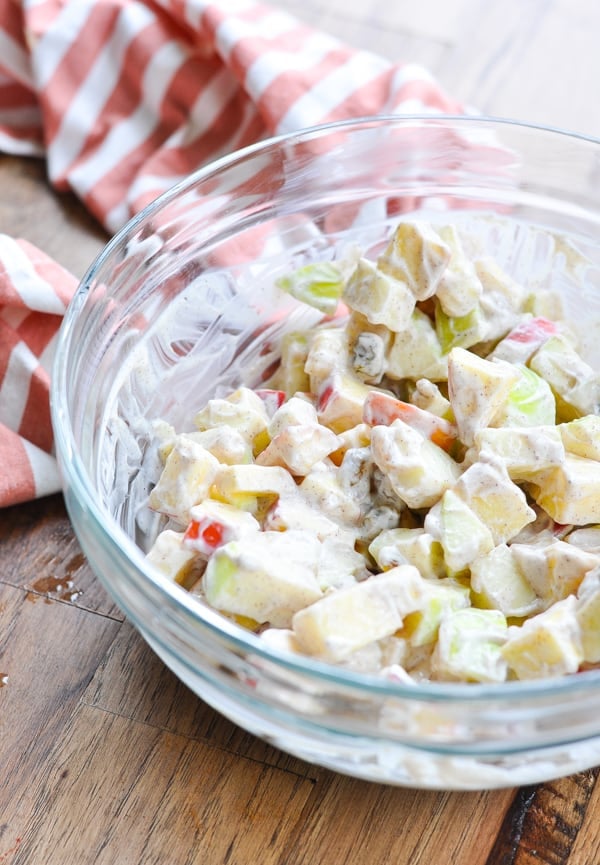 Creamy apple salad in a glass bowl. Diced apples and raisins are coated in a creamy Greek yogurt dressing with apple pie spice.