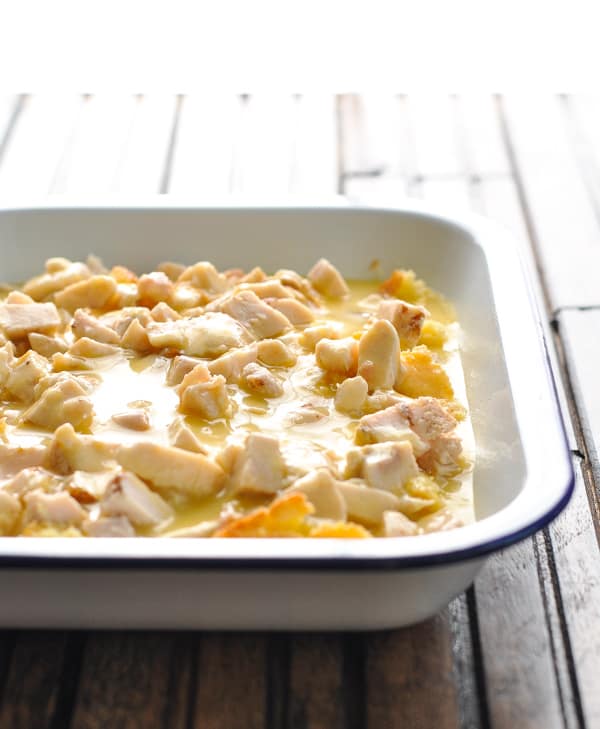 Layered chicken and sauce for Cowboy Casserole in baking dish