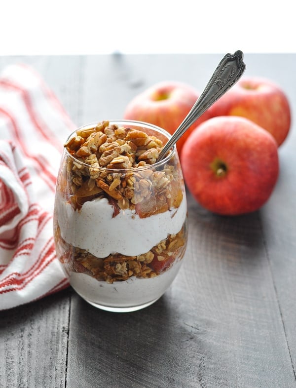 Apple crisp yogurt parfait made with greek yogurt and granola in a glass with a spoon inside