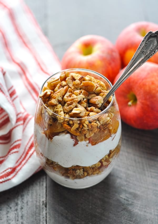 Layers of apple crisp healthy yogurt parfait in a glass with a spoon