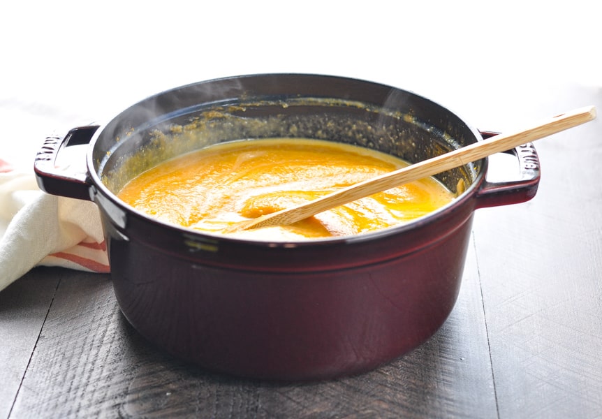 Cast iron pot full of steaming vegan healthy pumpkin soup made with coconut milk