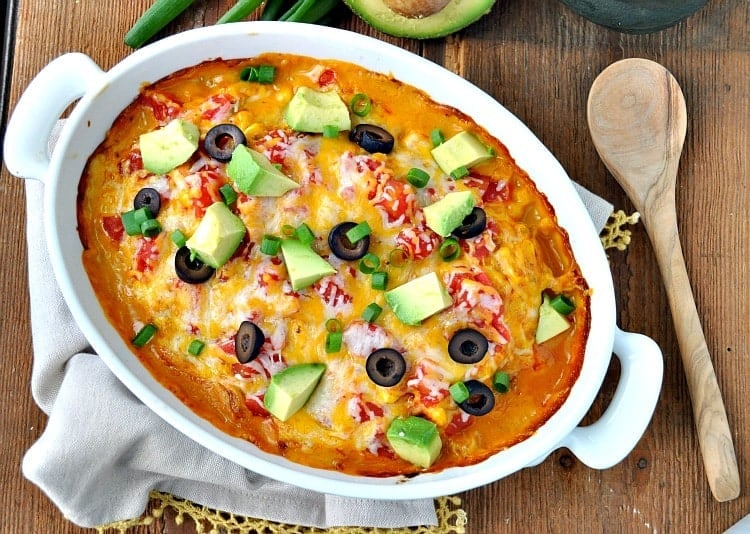 An overhead image of freshly baked chicken taco casserole, garnished with diced avocado, black olives, and green onions.