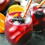 Glass of Hallowine Sangria with orange and black straws and text overlay