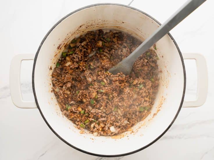 Adding the spices to the pot of chili.