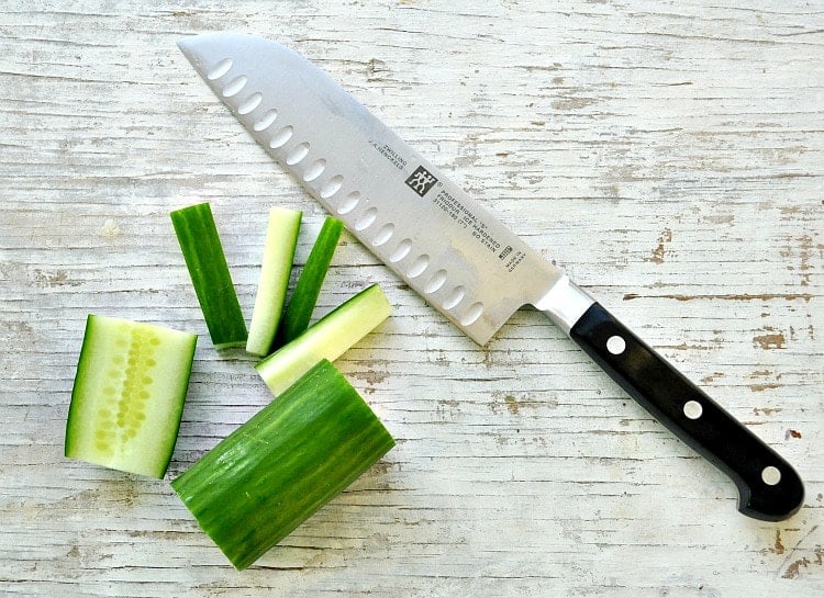 cucumber chopped up on a wooden surface with a knife
