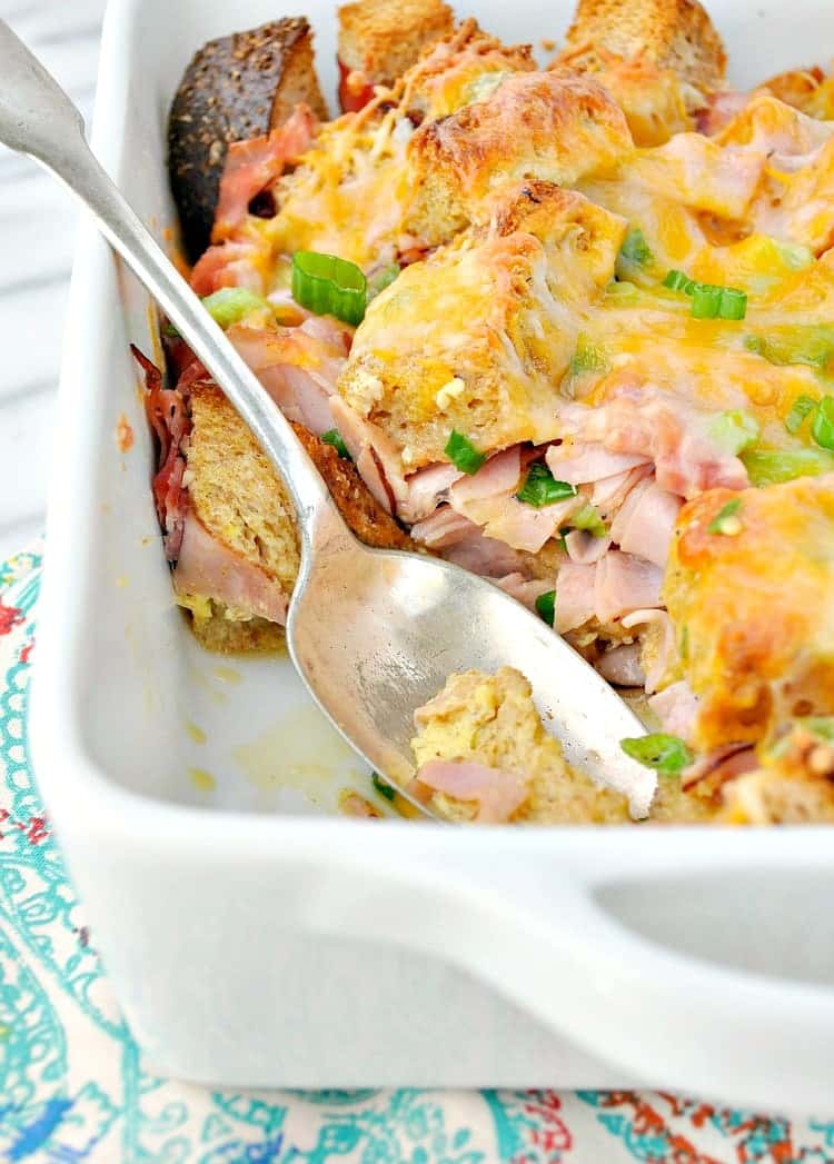 A casserole dish filled with a breakfast strata with a serving spoon