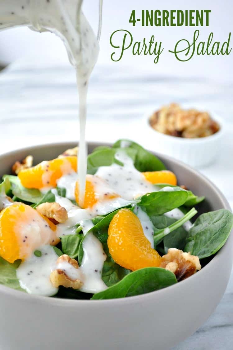 A bowl of spinach and mandarin salad, topped with a stream of creamy poppyseed dressing.