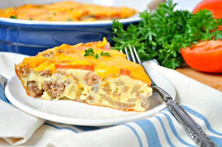 A slice of sausage and cheese pie on a white plate and topped with parsley