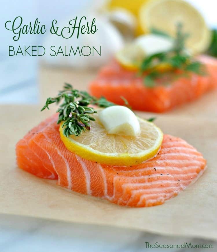 A close up of a fillet of salmon with garlic, herbs and lemon