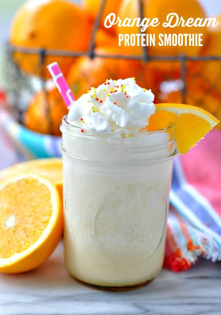 A mason jar filled with an orange smoothie and sliced oranges in the background.