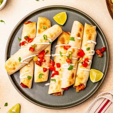 Square overhead shot of a plate of chicken taquitos.