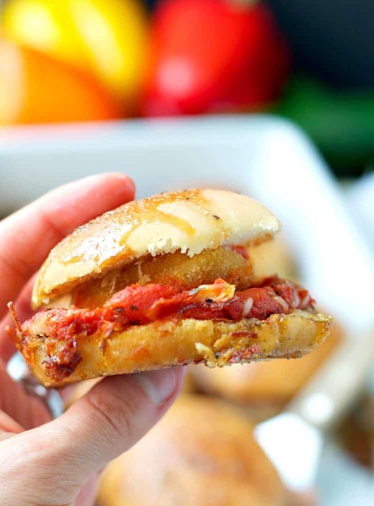 This easy Chicken Parmesan Sliders Casserole is the perfect weeknight dinner! | Chicken Parmesan Recipes | Italian Chicken | #chickenparmesan #sliders #theseasonedmom A hand holding chicken parmesan sliders
