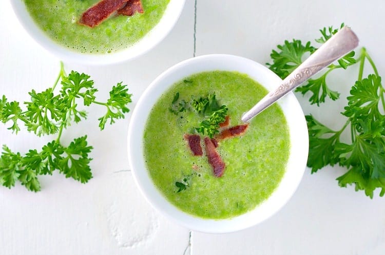Sweet pea soup in small white bowls topped with bacon and parsley