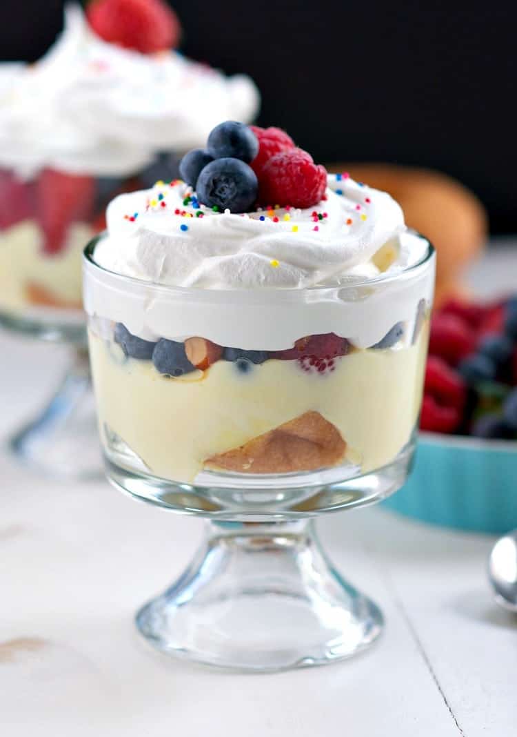 A side shot of a donut trifle topped with cream and berries