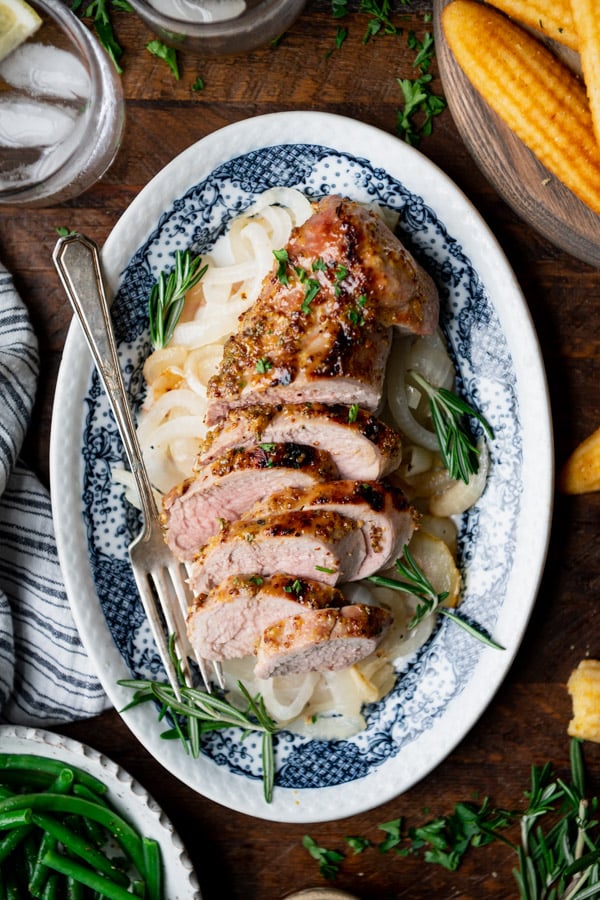 Oven roasted pork tenderloin recipe served on a blue and white plate on a wooden table.