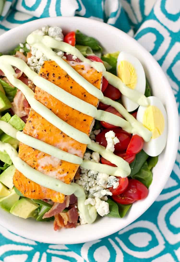 A close overhead shot of a salmon salad with avocado dressing drizzled over the top