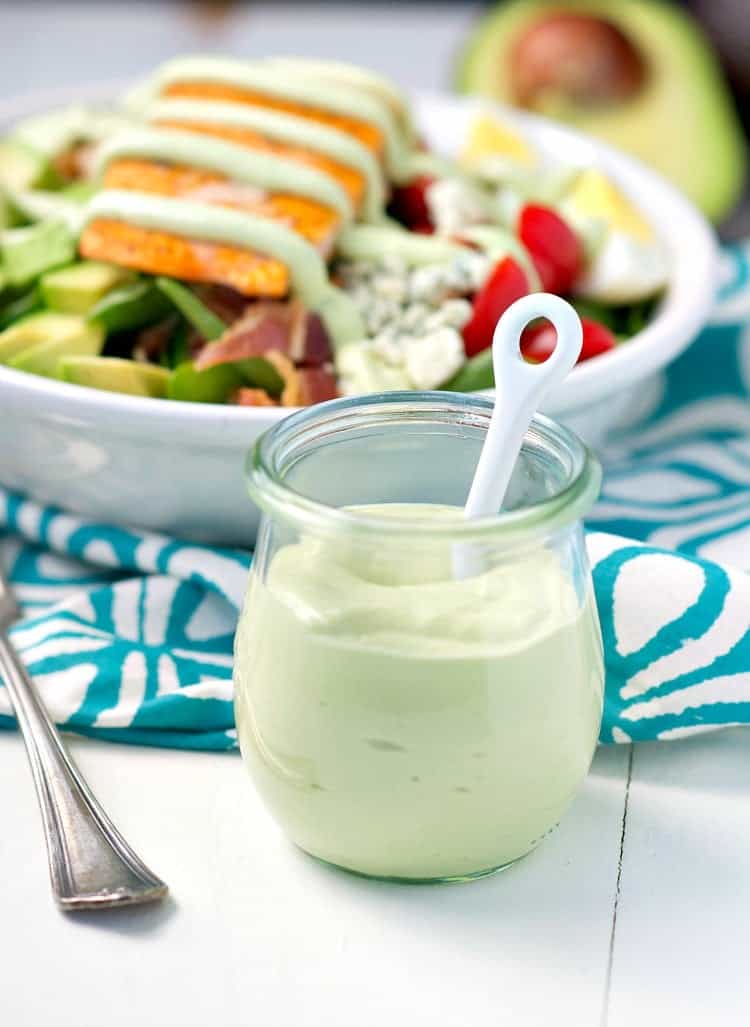 A salmon salad with avocado in a glass jar in front of it