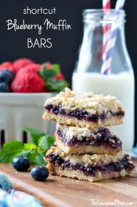 Blueberry muffin bars stacked on top of each other with milk in the background