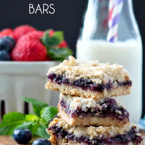 Blueberry muffin bars stacked on top of each other with milk in the background