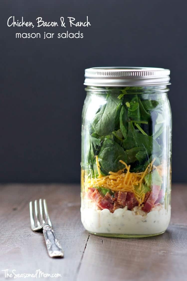 A mason jar on a wooden surface filled with a chicken and bacon ranch salad