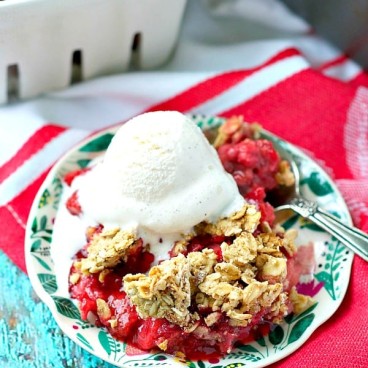 Healthy strawberry crisp on a plate with a scoop of vanilla ice cream