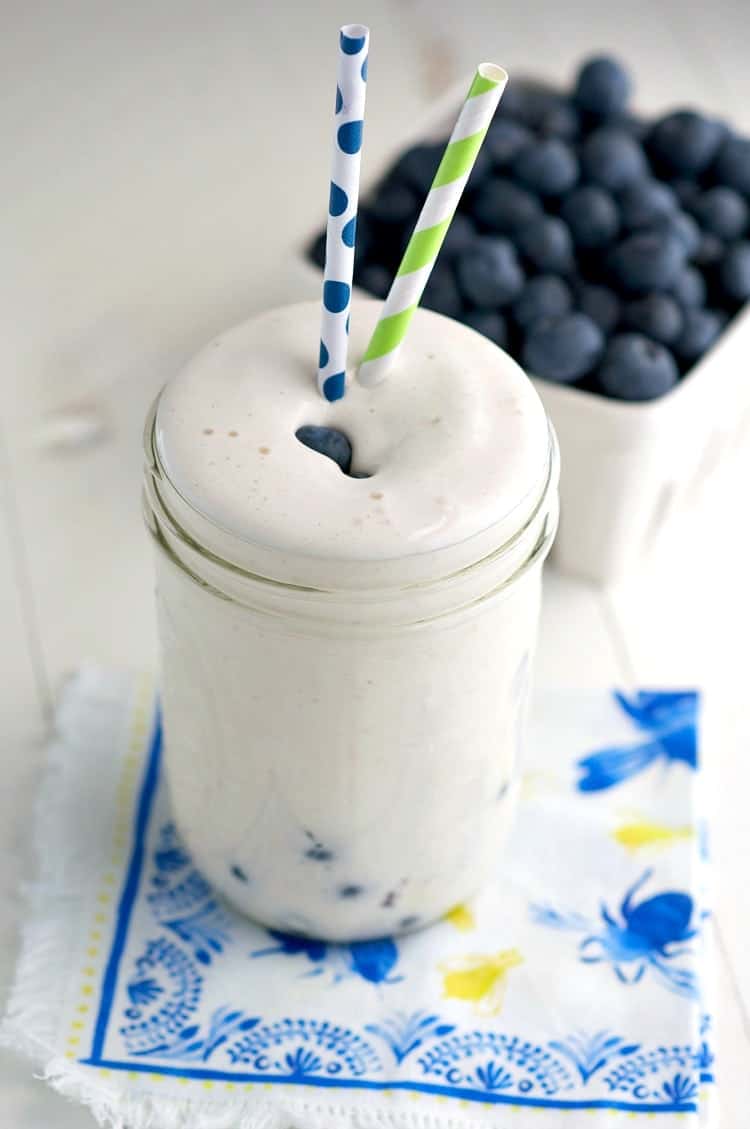 An overhead shot of blueberry muffin protein smoothie with two straws
