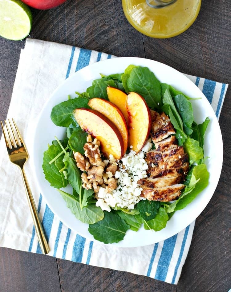 An overhead shot of a nectarine salad with grilled chicken and walnuts