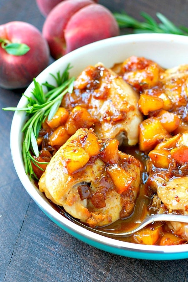 A close up of peach glazed chicken in a blue skillet