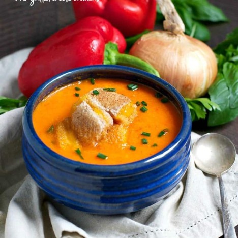 Roasted red pepper soup in a blue bowl topped with croutons