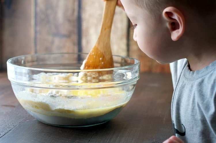 A boy mixing a baking mix in a bowl for cinnamon sugar puff muffins