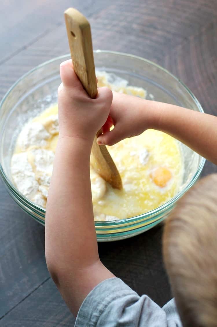 A small boy mixing a cake mix for cinnamon sugar puff muffins