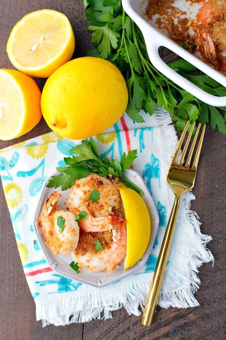 An overhead shot of garlic butter shrimp on a plate with lemons