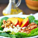 A grilled chicken and nectarine salad on a plate with walnuts