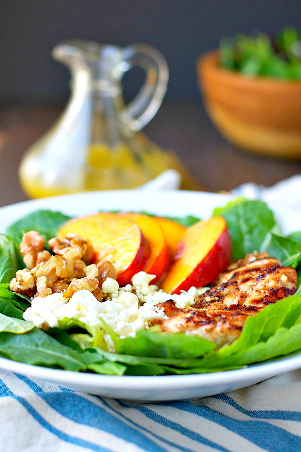 A grilled chicken and nectarine salad on a plate with walnuts