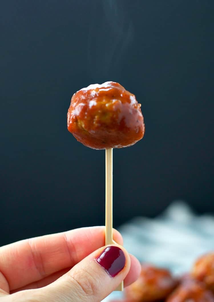 Someone holding barbecue meatballs on a cocktail stick